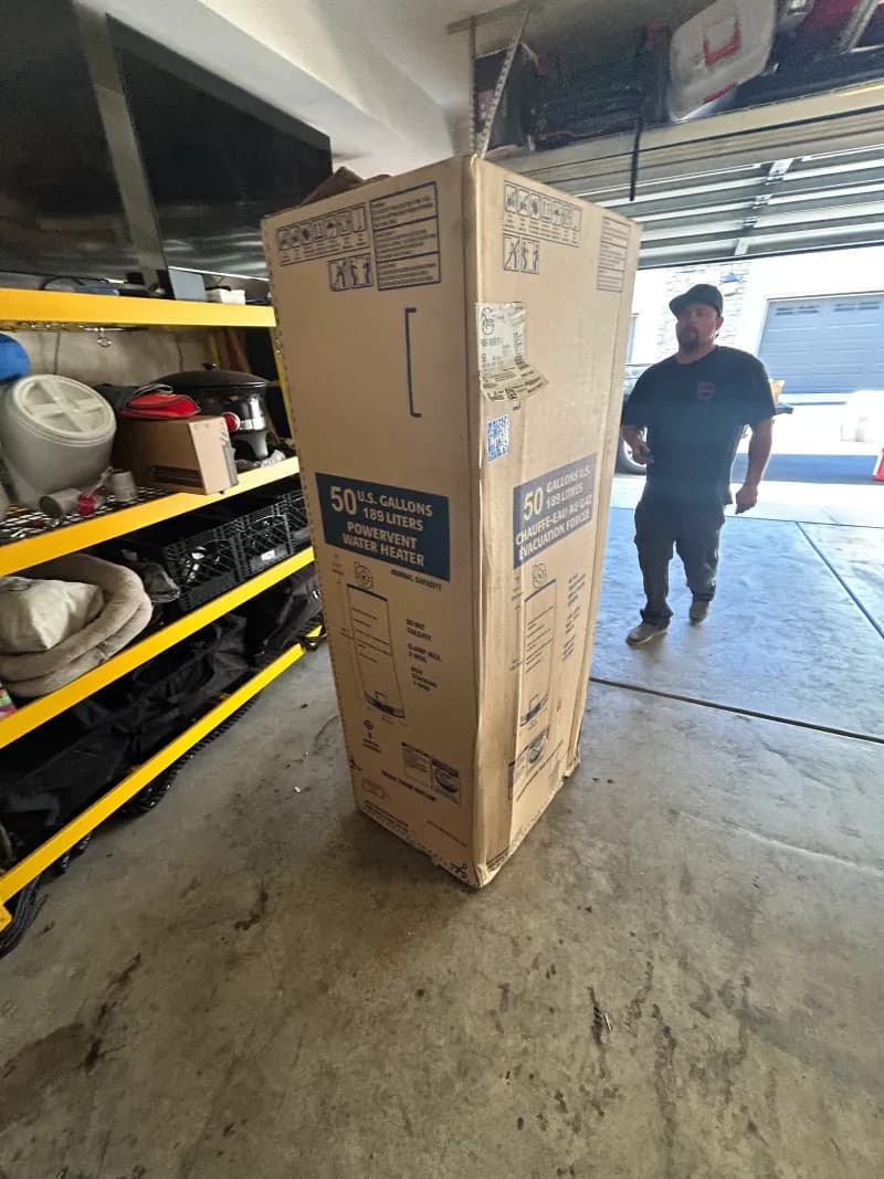 Regal Plumbing & Rooter technician carrying a 50-gallon power vent water heater for installation in Fontana, CA